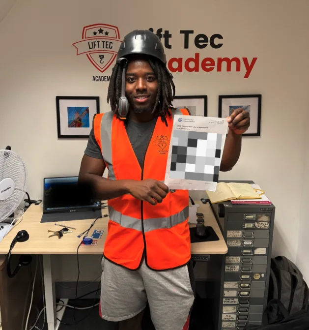 Student holding his CPCS technical test letter of achievement at the Lift Tec Academy office