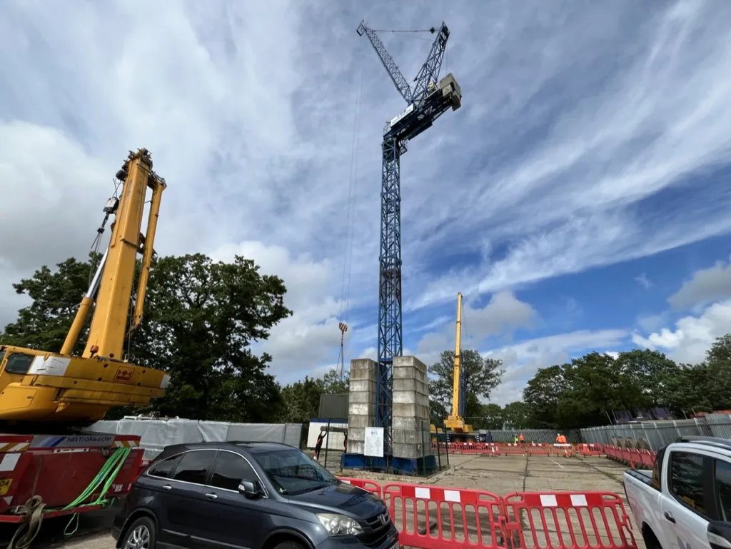 Tower crane erected in the training yard alongside mobile cranes under a blue sky