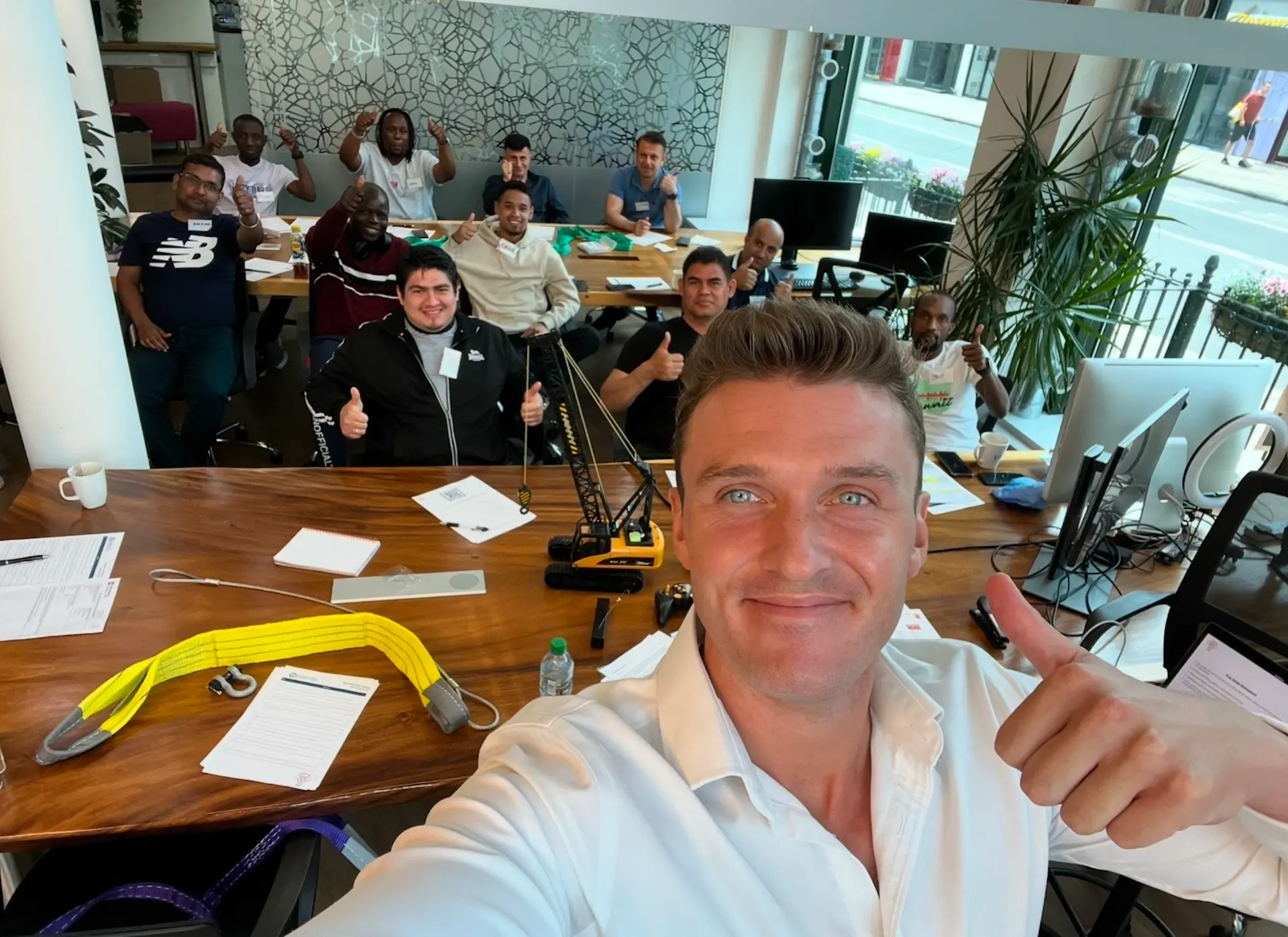 Training group in the Lift Tec classroom giving a thumbs up around the table